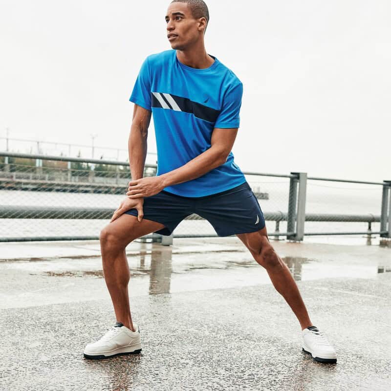 man stretching wearing a pair of white nautica sneakers