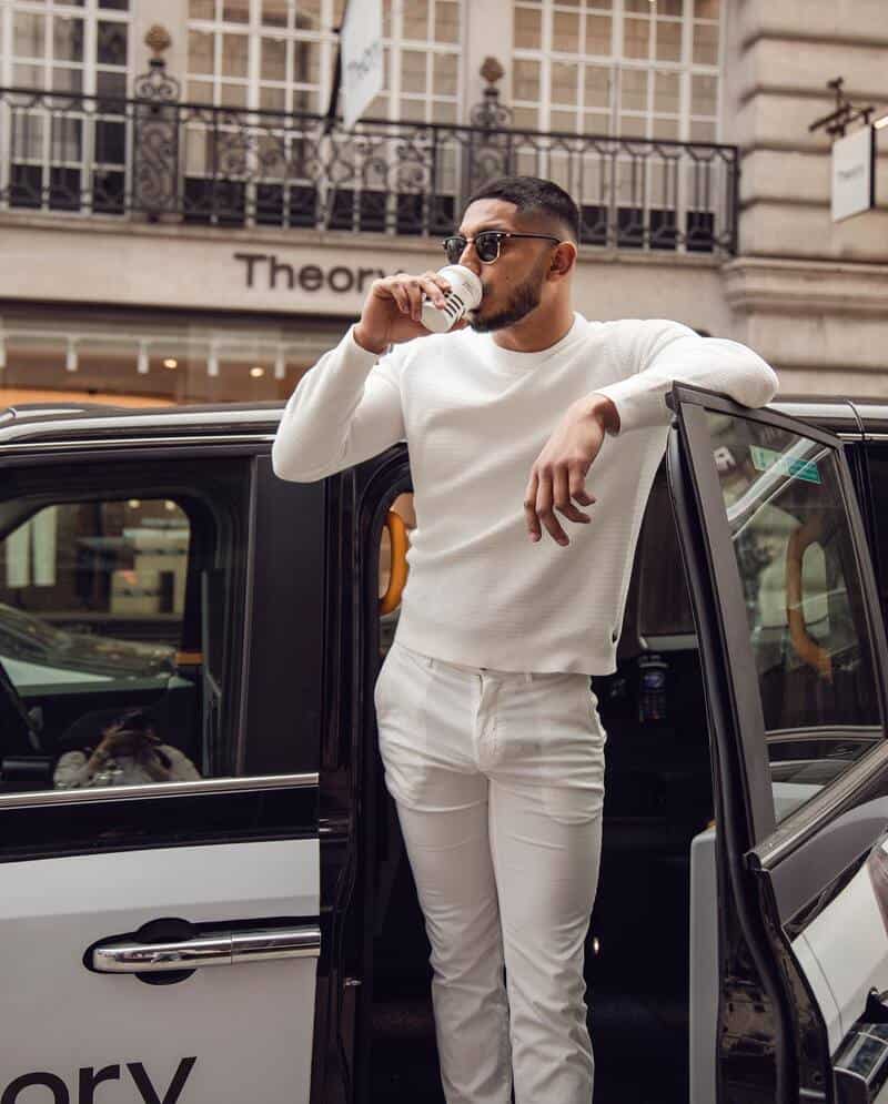 man in white outfit drinking from a disposable cup