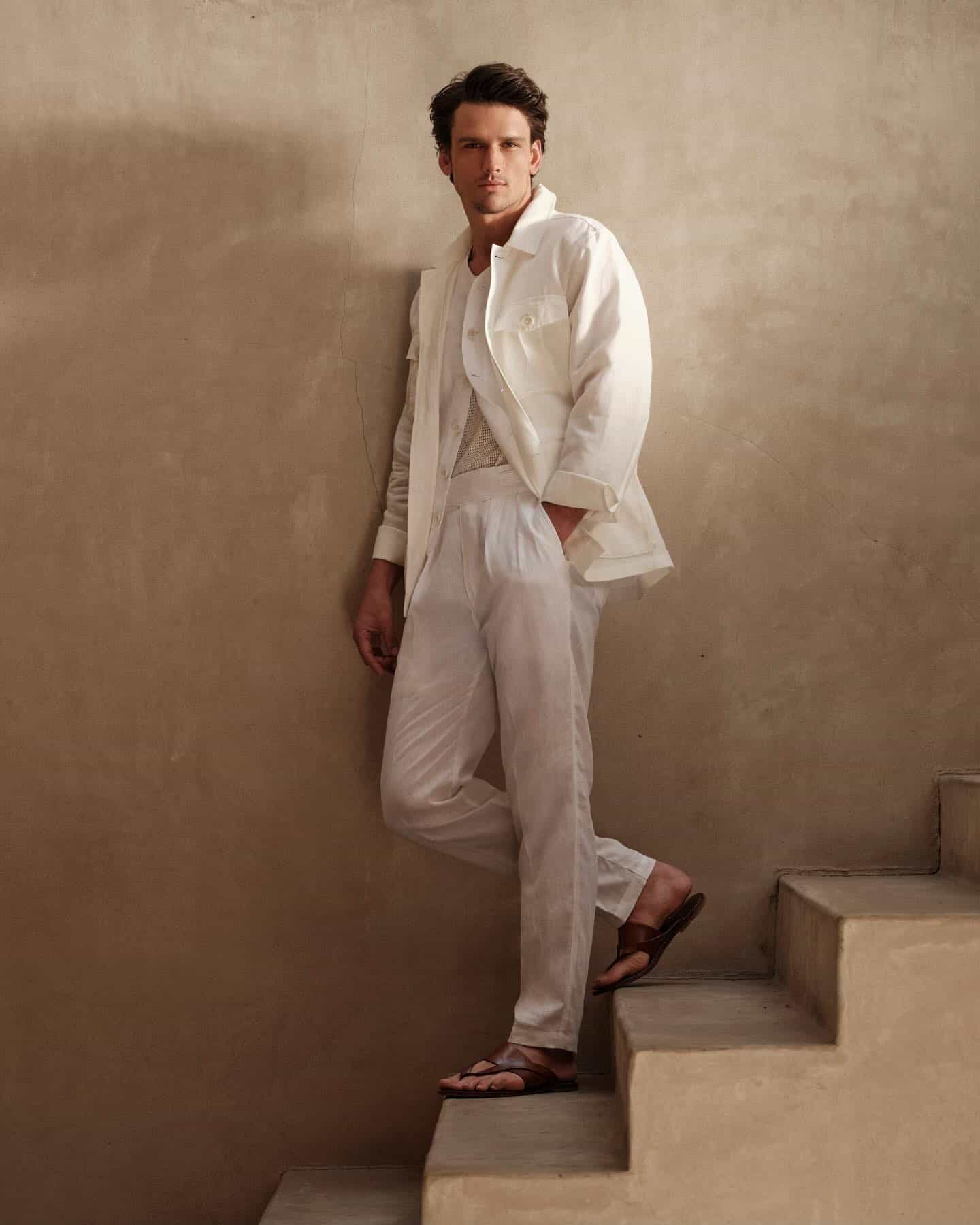 man in a white outfit standing on the stairs