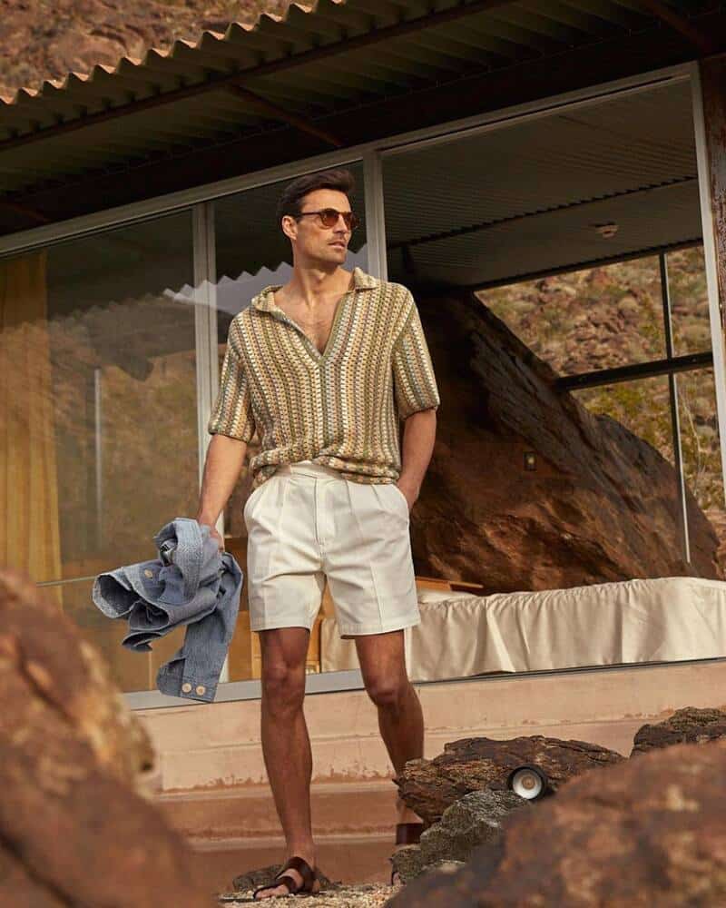 man wearing a knitted polo shirt and pleated shorts
