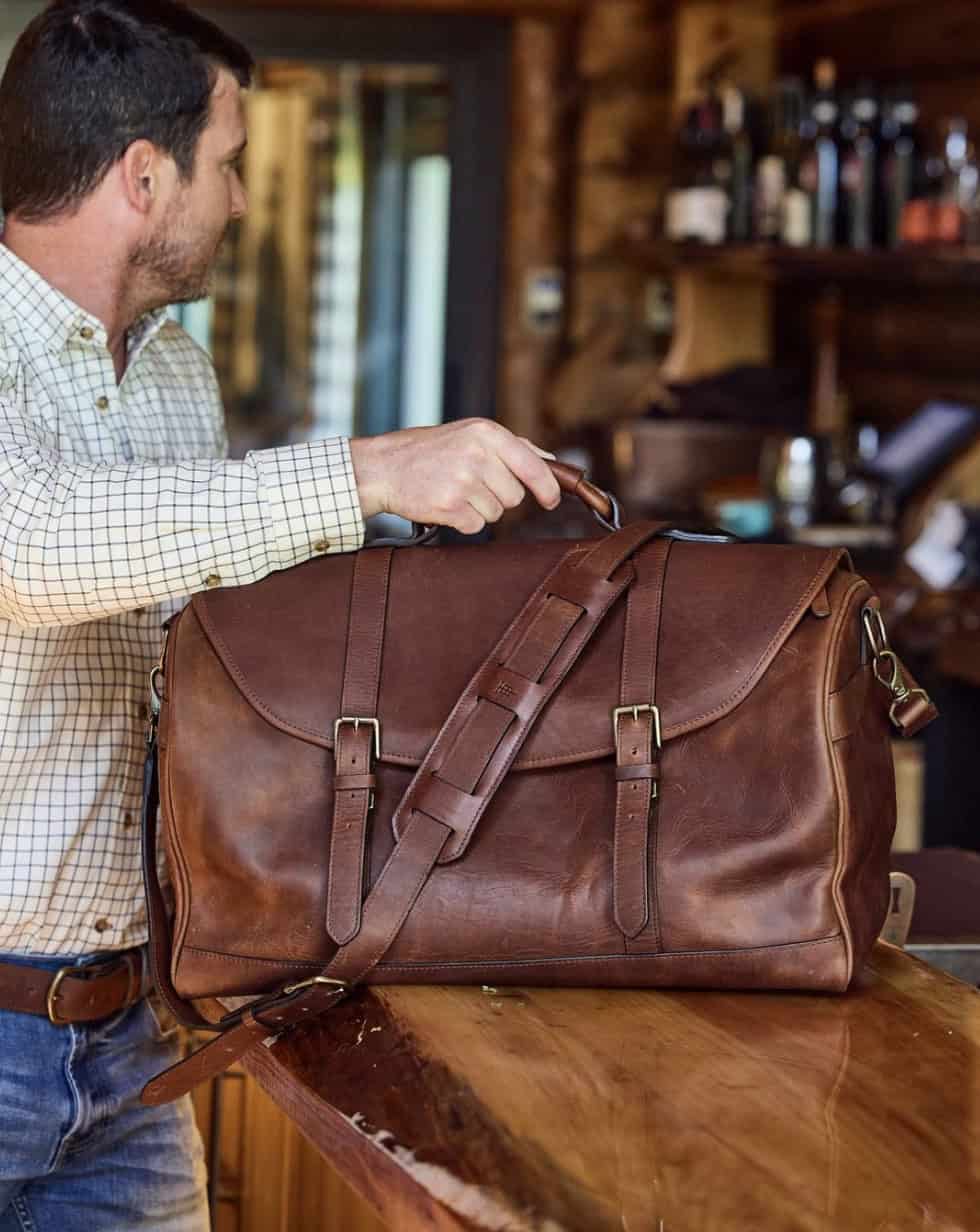 Man holding the best weekender bag for men on a counter