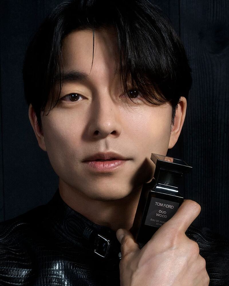 man holding a bottle of tom ford oud wood