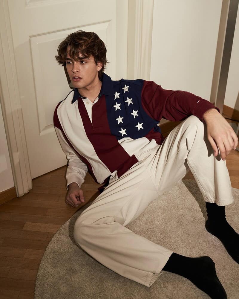 man on the floor wearing a long sleeved polo shirt and white jeans