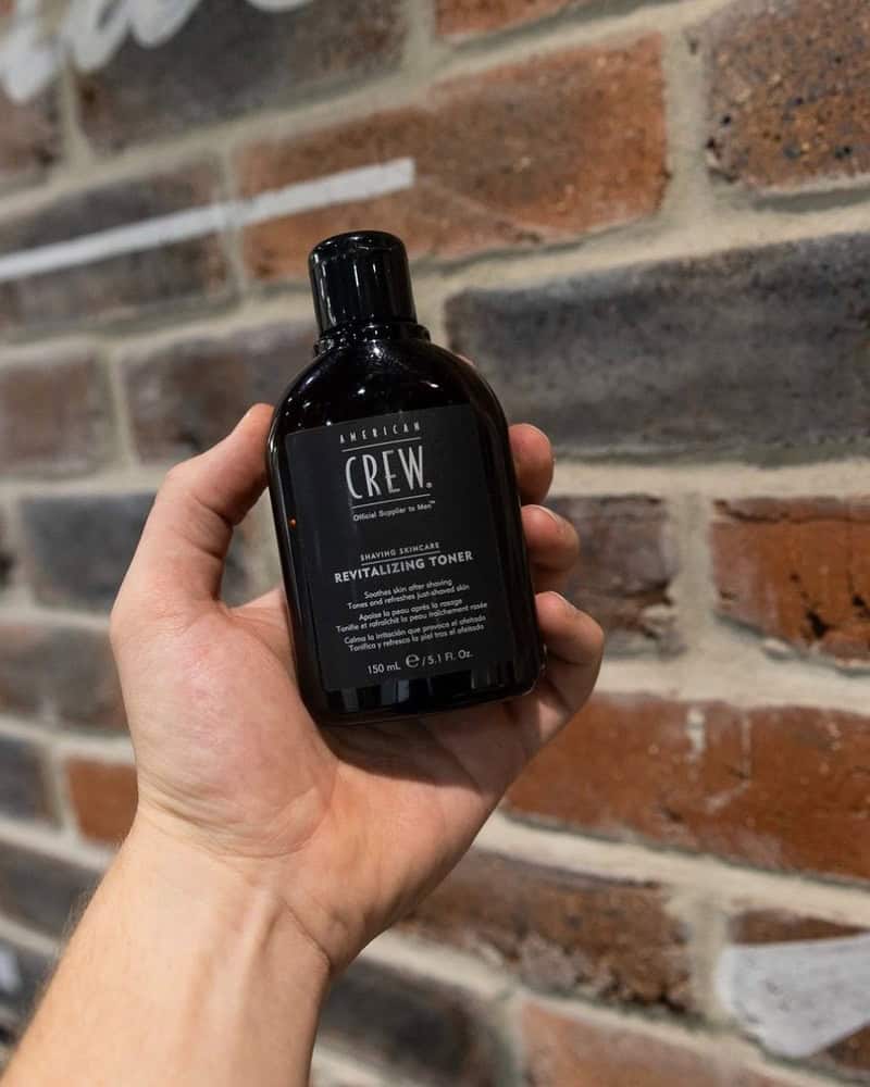 holding a bottle of american crew revitalizing toner