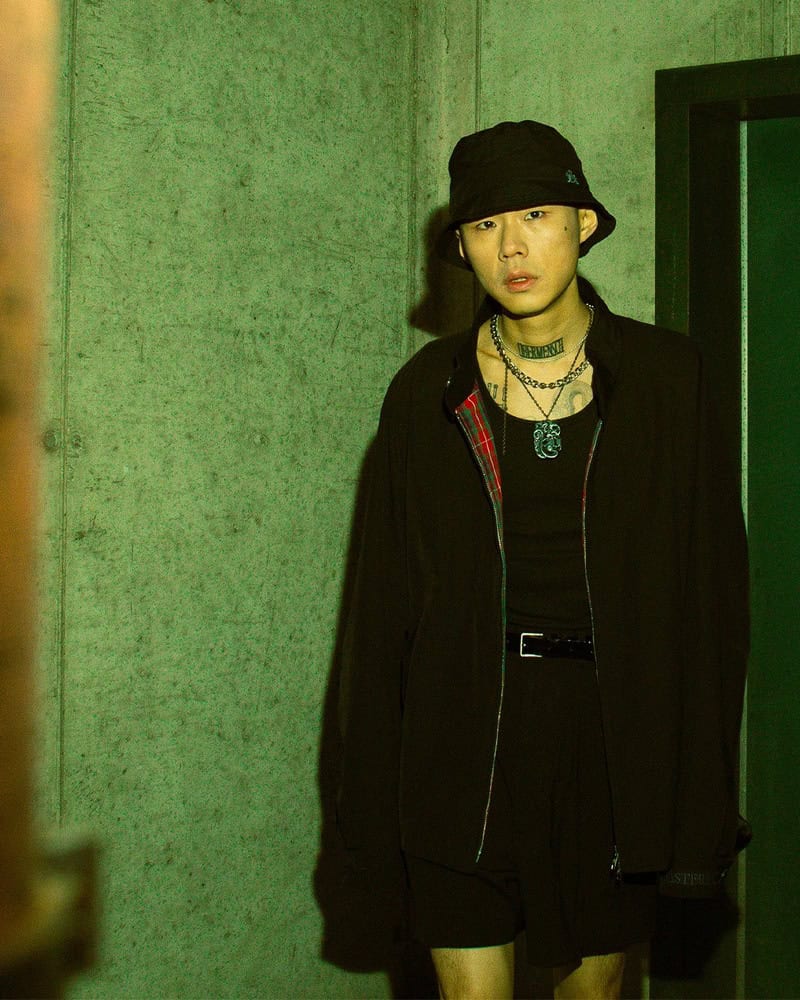 man in black outfit wearing a bucket hat by baracuta