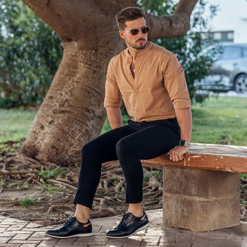 man sitting on a concrete bench wearing a pair of bruno marc casual dress derby sneakers