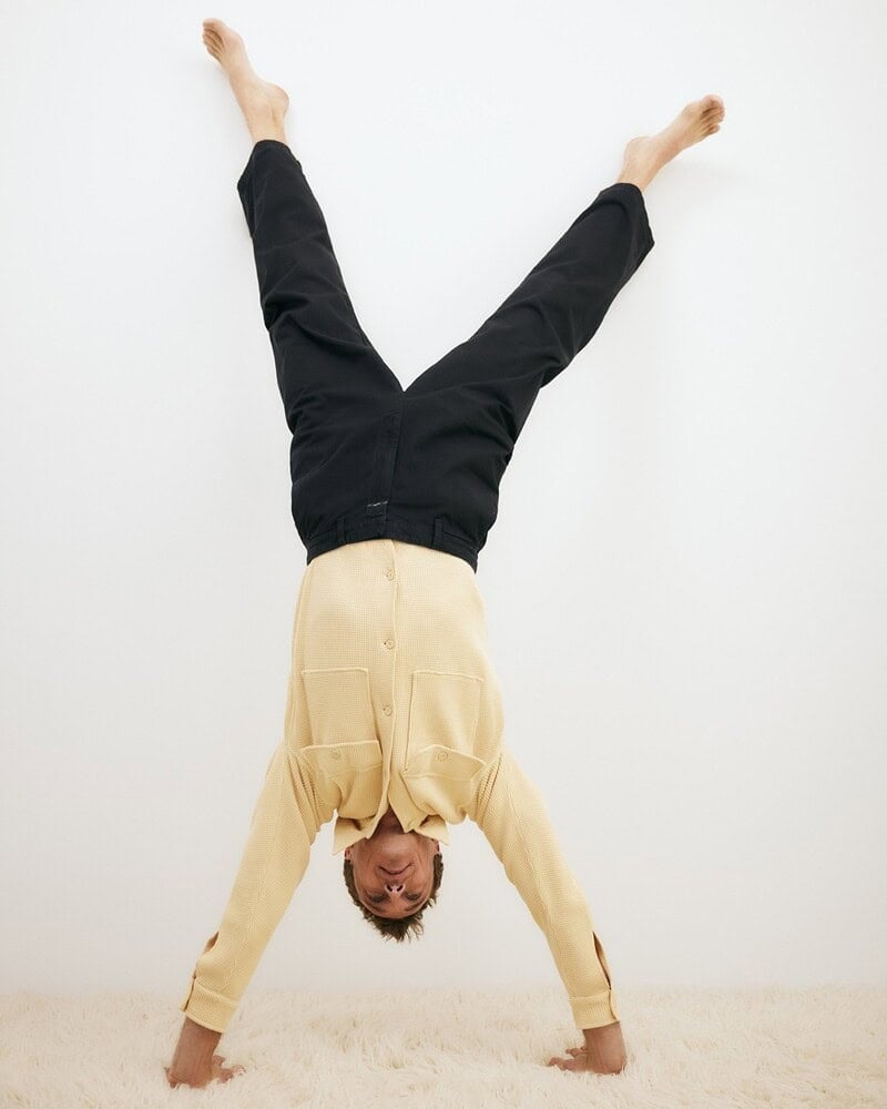 man in black pants performing a handstand
