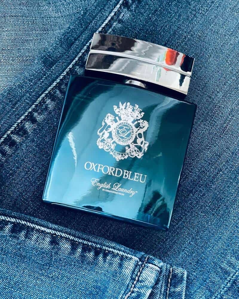 a bottle of oxford bleu by english laundry on top of a pair of jeans
