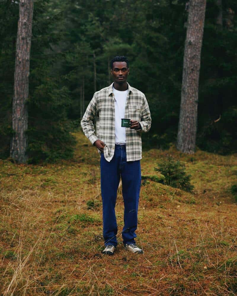 man in the woods carrying a green cup by foret
