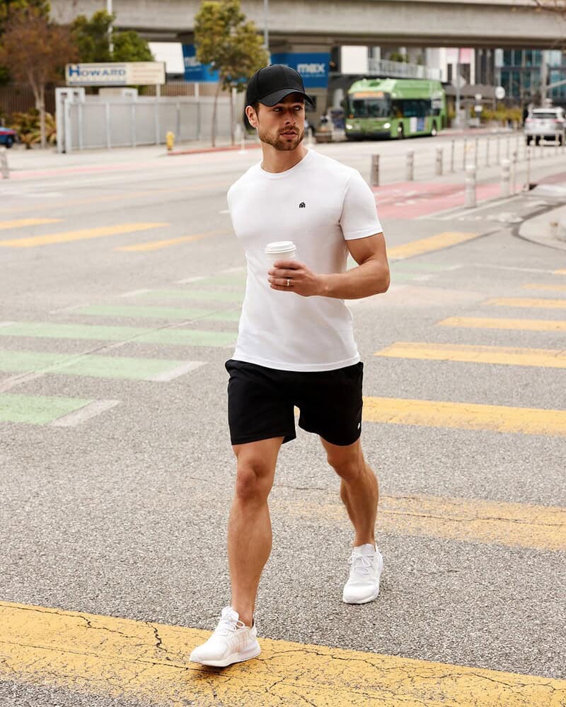 man crossing the street while holding a disposable cup