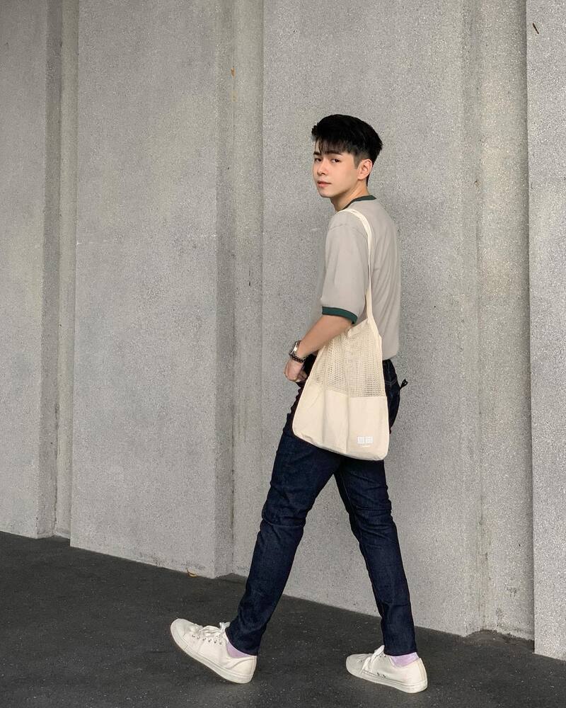 man wearingt shirt and jeans carrying a tote bag on his shoulders