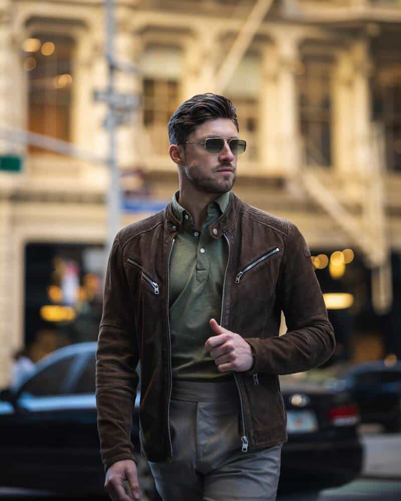 man with sunglasses wearing a brown suede jacket and olive green polo shirt