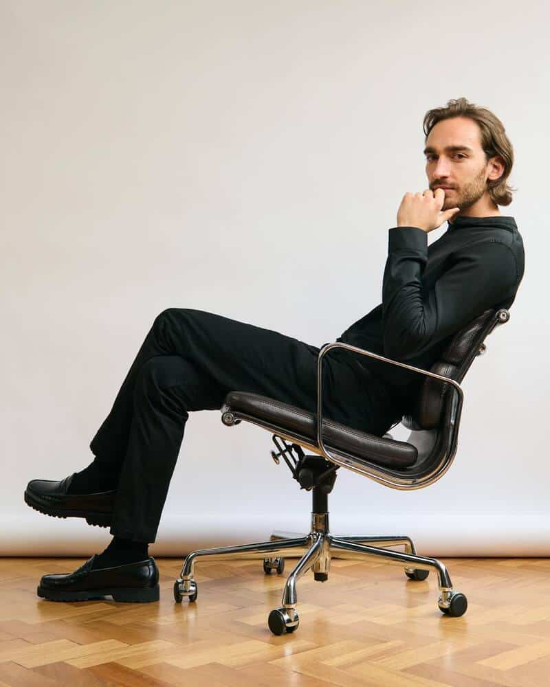 man sitting on an office chair wearing black shirt and pants