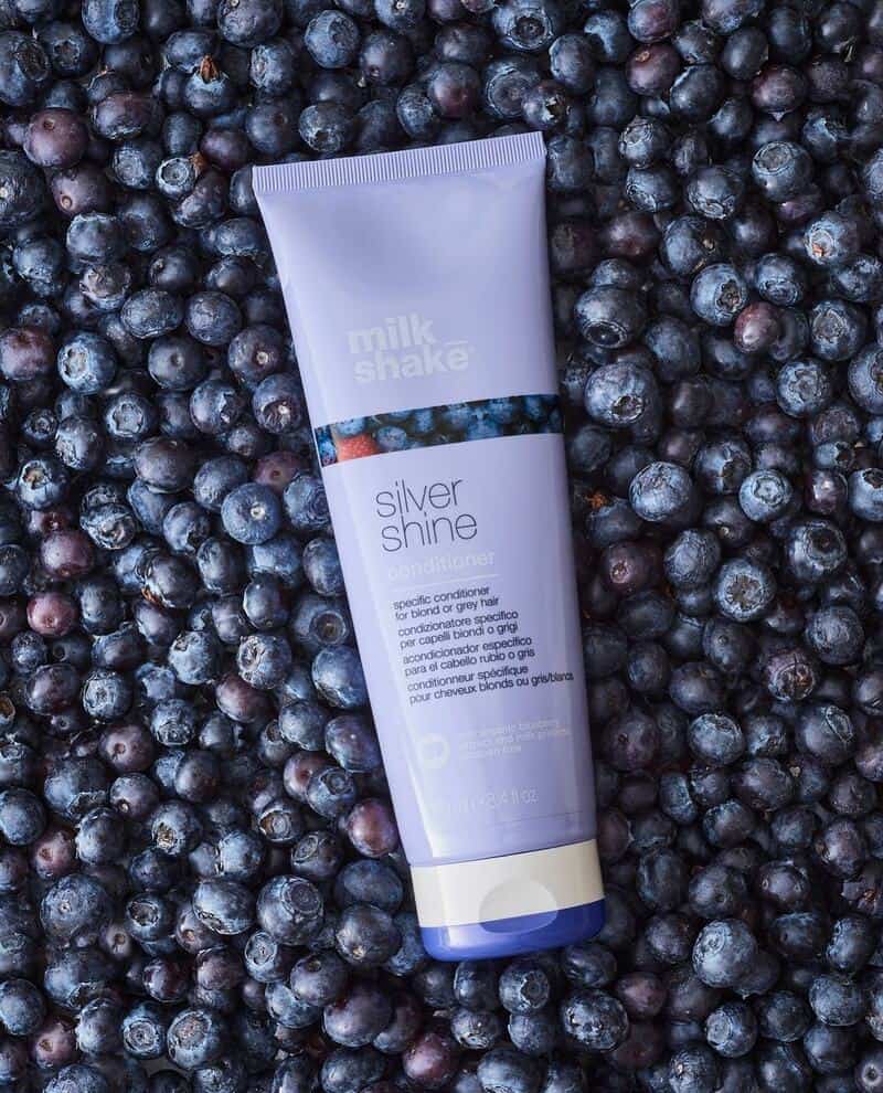 a bottle of milk_shave silver shine conditioner on top of blueberries