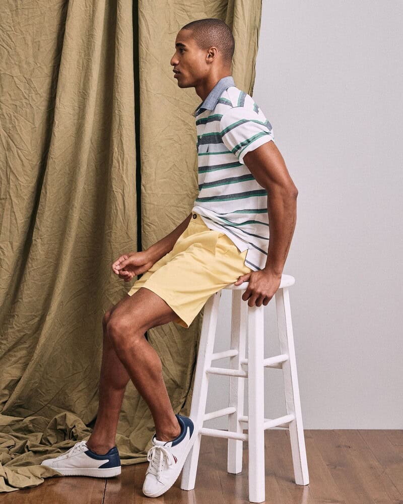 man sitting on a stool wearing a polo shirt and shorts
