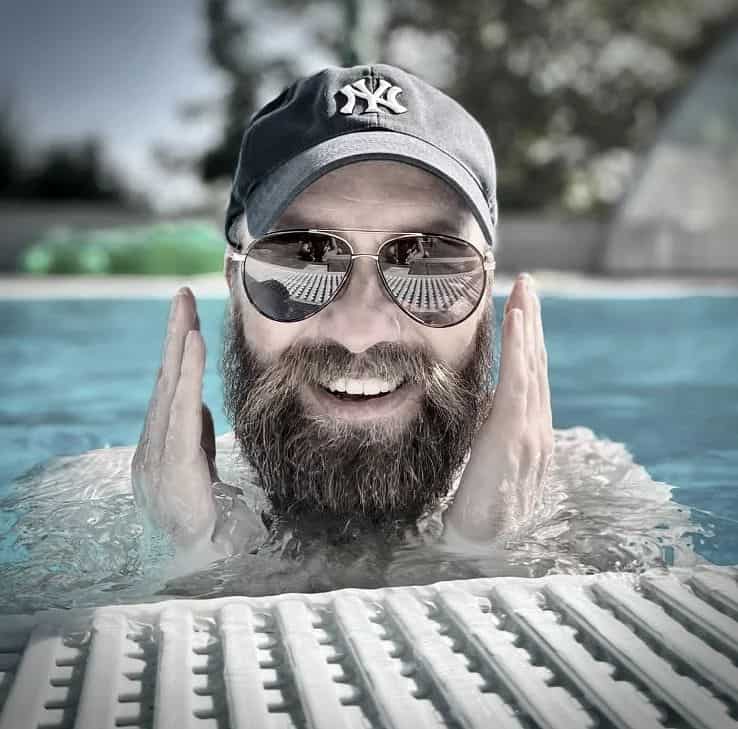 man in the pool wearing a hat and sunglasses