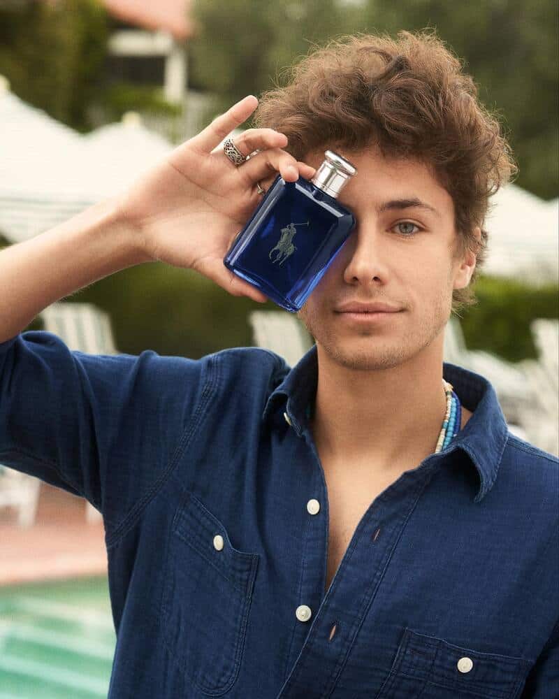 man covering his face with a bottle of Polo Blue Cologne by Ralph Lauren
