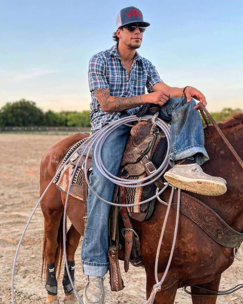 man in a checked shirt and jeans riding a horse
