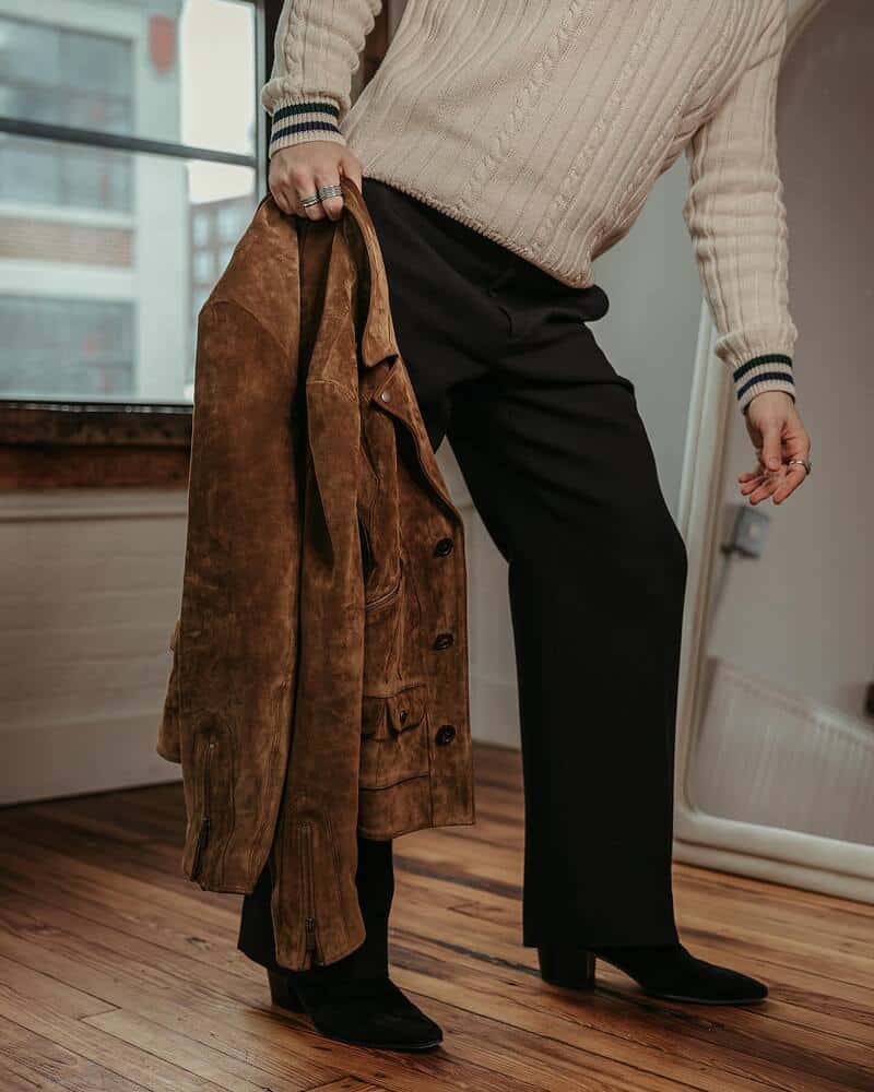 man holding a suede jacket by the collar