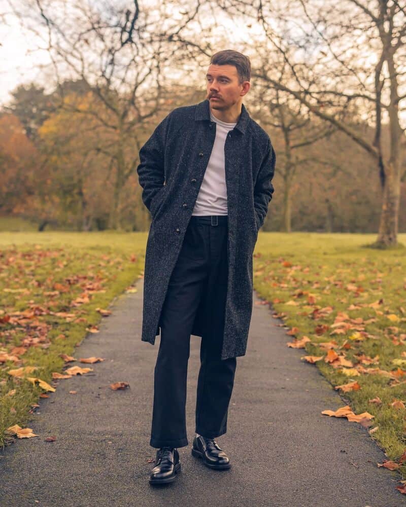 man in a long coat wearing a pair of black derby shoes