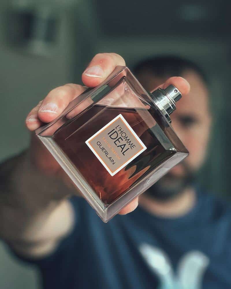 man holding a bottle of L'Homme Ideal Eau De Parfum by Guerlain
