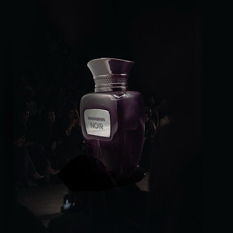 a large bottle of Al Haramain Noir in a dark room surrounded by people