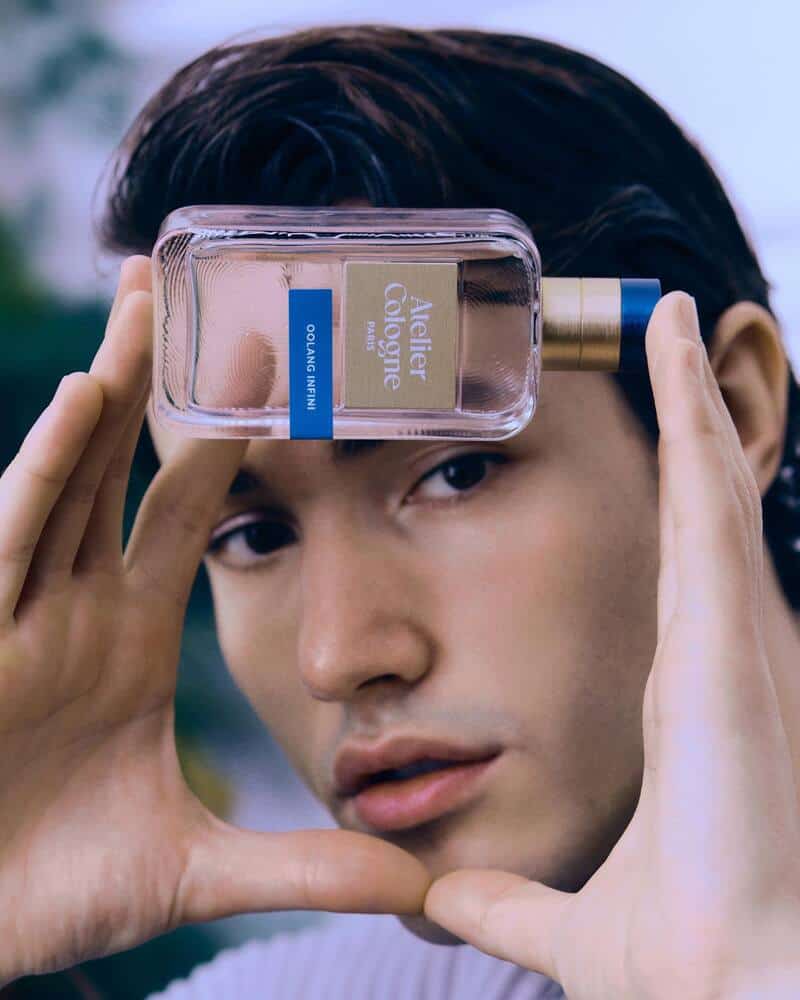 man holding the Oolang Infini Cologne by Atelier Cologne in-front of face