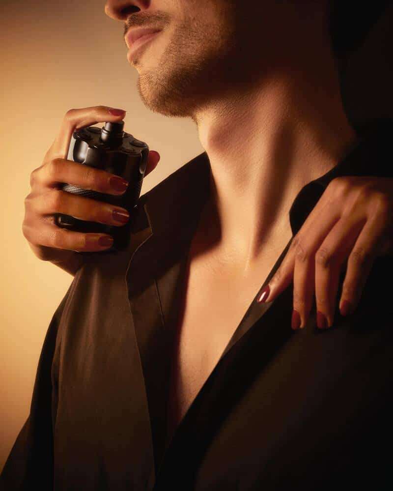 woman spraying the Azzaro The Most Wanted cologne to a man's neck