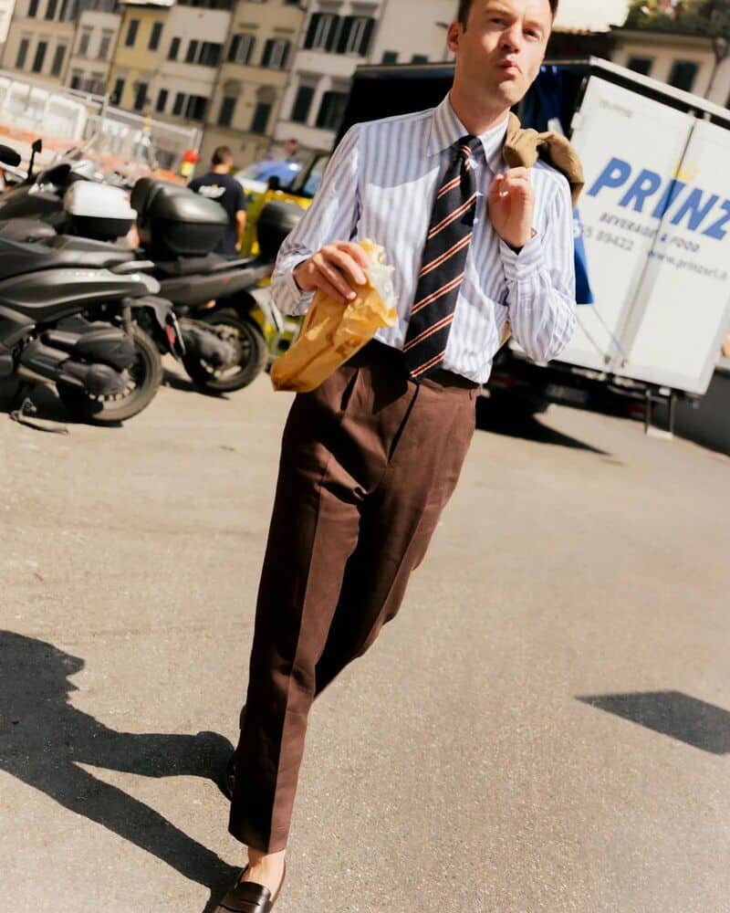 man eating a sandwich wile walking on the street