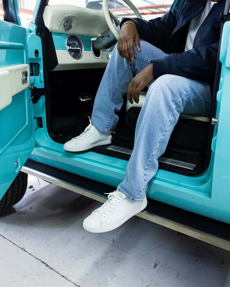 man in the drivers seat wearing a pair of white clae sneakers