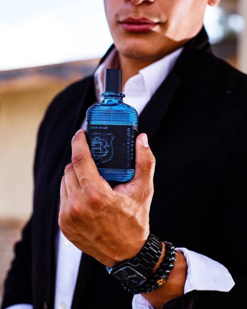 man holding a bottle of C.O. Bigelow Elixir Blue Cologne