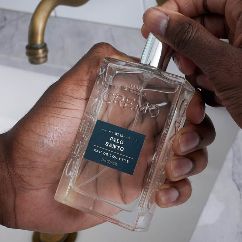 holding a bottle of Palo Santo Cologne by Cremo