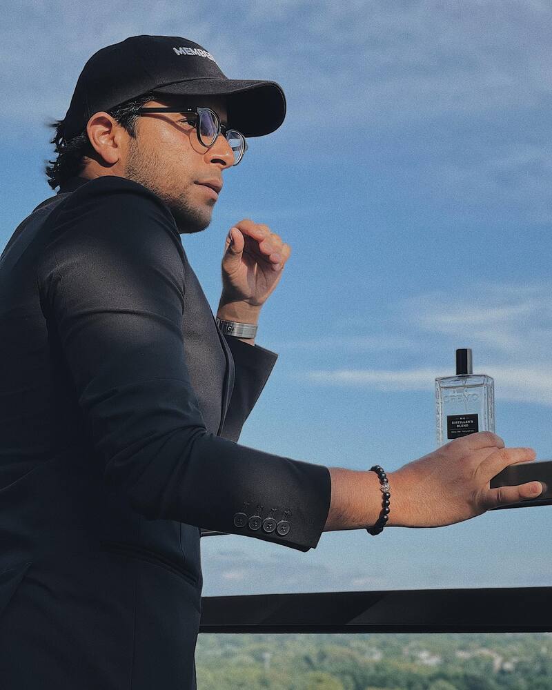 man enjoying the mountain view while holding a bottle of Cremo cologne