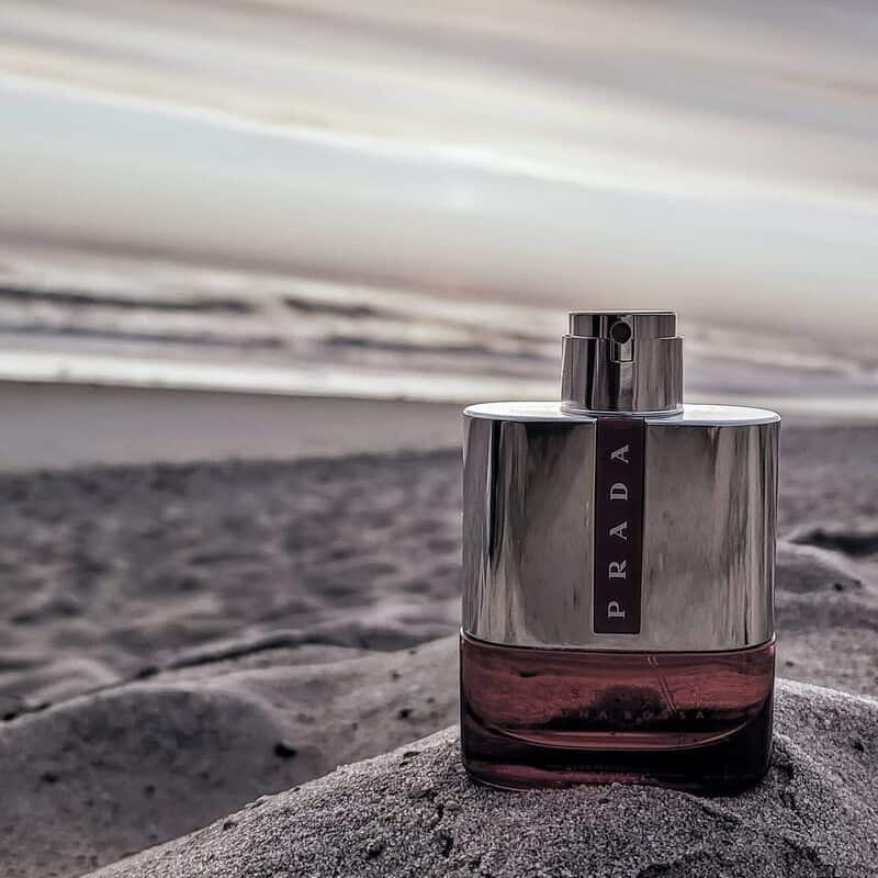 a bottle of Prada Luna Rossa Sport in a sandy beach