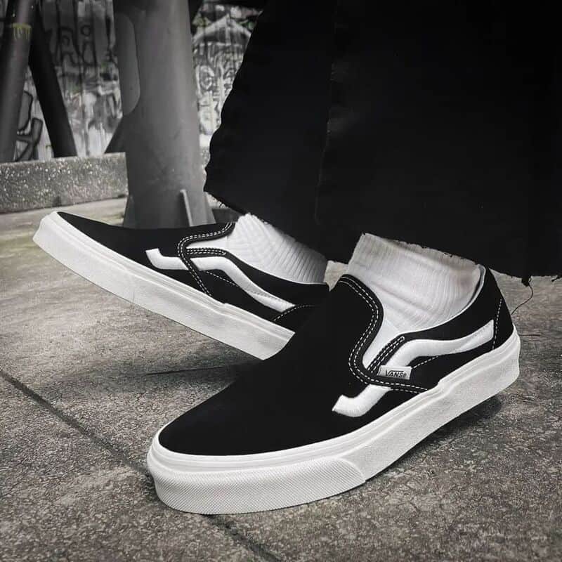 wearing a pair of black slip-ons by Vans