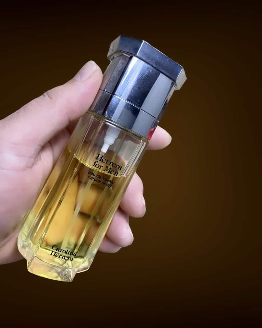 holding a bottle of Herrera For Men Cologne by Carolina Herrera