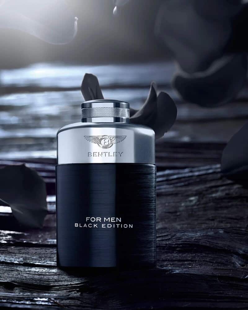 a bottle of Bentley Black Edition for men with black petals falling in the background