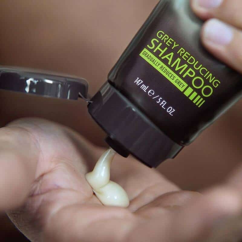 A man squeezing the Just for Men Grey Reducing shampoo on his palm