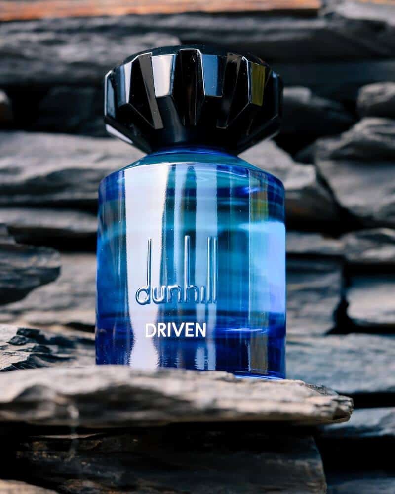 a bottle of Dunhill Driven Cologne on top of a flat rock