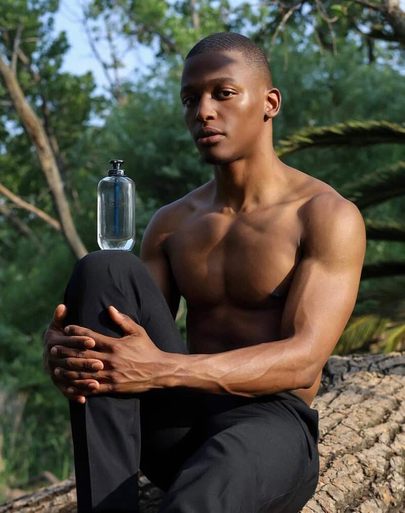 a man with a bottle of Coach Open Road cologne on his knee