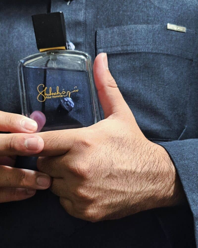man holding a bottle of Shuhrah Pour Homme Cologne