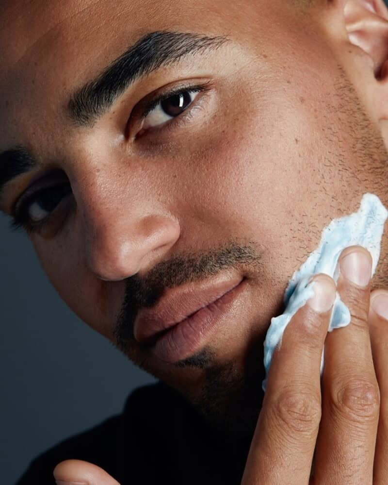 A man applying shaving cream on his face