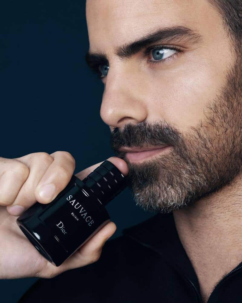 man holding a bottle of Dior Sauvage Elixir by the chin
