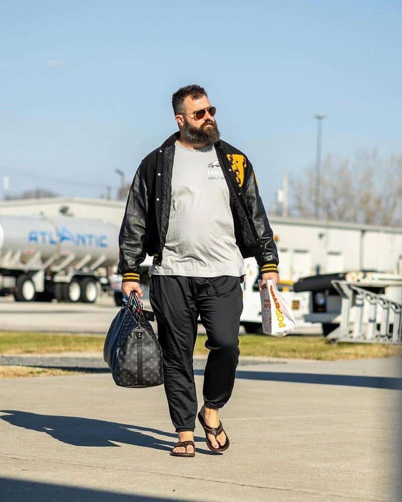 man with luggage walking wearing olukai flip flops