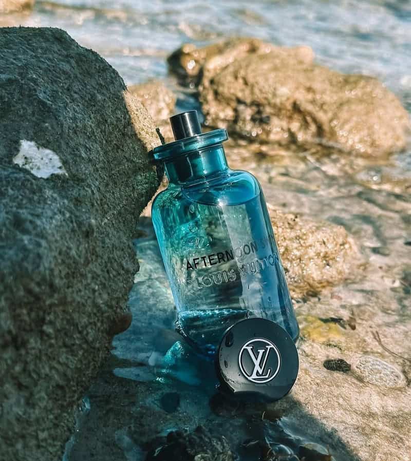 a bottle of Louis Vuitton Afternoon Swim cologne by the sea