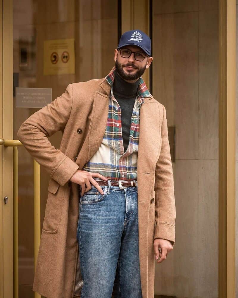 man wearing a plaid shirt and jeans layered with a long coat