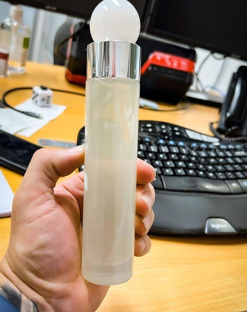 holding a bottle of perry ellis white cologne