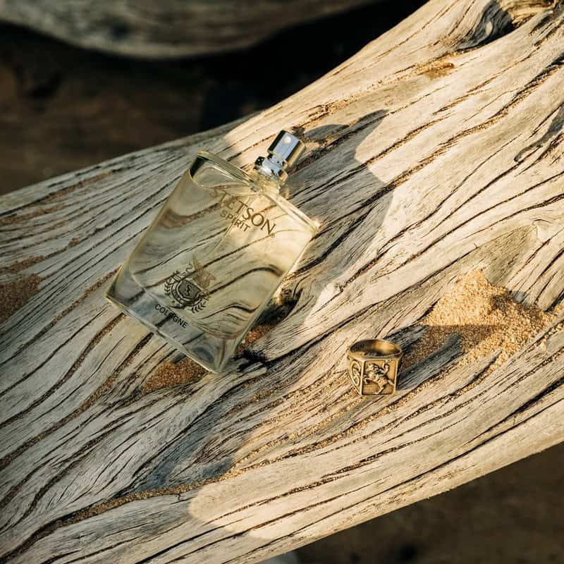 a bottle of Stetson Spirit Cologne and a ring on top of a dry tree trunk