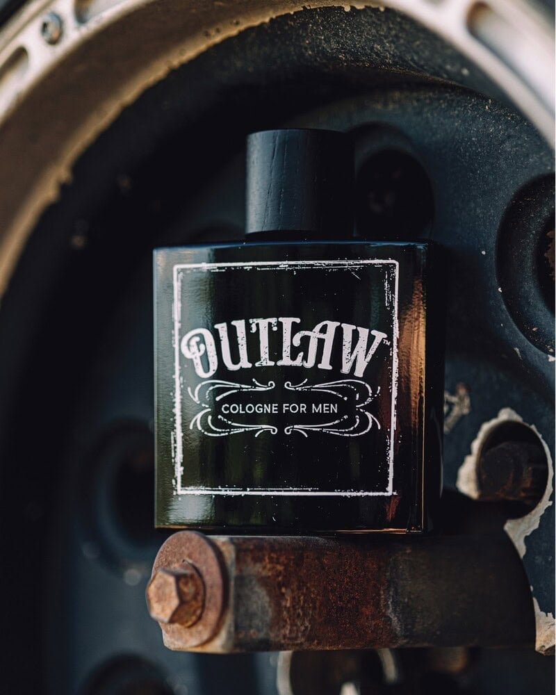 a bottle of Outlaw Cologne for men on a wheel hub