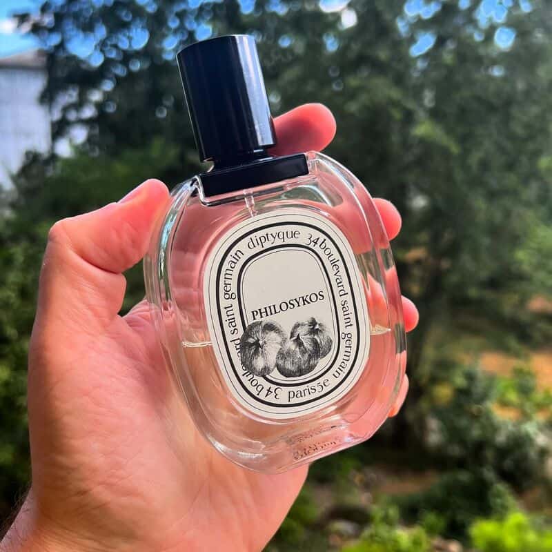 holding a bottle of Philosykos Cologne by Diptyque